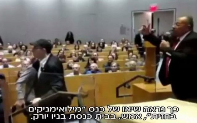 Bassem Eid, à droite, tente de parler pendant qu'un perturbateur est repoussé de la scène après avoir tenté de l'agresser dans une synagogue de New York, le 26 octobre 2017. (Crédit : capture d'écran Deuxième chaîne) Bassem Eid, à droite, tente de parler pendant qu'un perturbateur est repoussé de la scène après avoir tenté de l'agresser dans une synagogue de New York, le 26 octobre 2017. (Crédit : capture d'écran Deuxième chaîne)