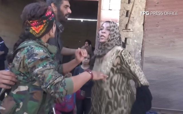 Une femme arrache les vêtements noirs imposés par l'Etat islamique pour célébrer la libération de Raqqa, le 13 octobre 2017. (Crédit : capture d'écran YouTube/YPG)