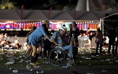 Un homme en chaise roulante est conduit vers la sortie du festival Route 91 Harvest, après des coups de feu, à Las Vegas, dans le Nevada, le 1er octobre 2017. (Crédit : David Becker/Getty Images/AFP)