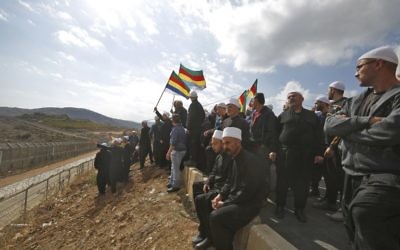 Des hommes druzes dans le Golan israélien se rassemblent à proximité de la frontière syrienne, brandissant leur drapeau communautaire, après avoir entendu parler d'un attentat suicide à la bombe dans le village druze syrien de Hader, le 3 novembre 2017 (Crédit :  Jalaa Marey/AFP)