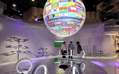 Des visiteurs observent le globe orné de drapeaux durant la COP23, la Conférence de Bonn de 2017 sur les changements climatiques, le 7 novembre 2017 à Bonn, en Allemagne. (Crédit : AFP/Oliver Berg)