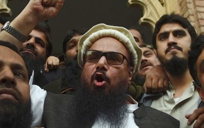 Le chef pakistanais de l'organisation Jamaat-ud-Dawa (JuD) Hafiz Saeed (au centre) s'adresse aux médias après sa libération devant un tribunal de Lahore, le 22 novembre 2017, (Crédit : AFP PHOTO / ARIF ALI)