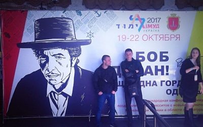 Les participants de la conférence du Limmud FSU, à Odessa, en Ukraine, s'appuient contre une affiche saluant le chanteur Bob Dylan, présenté comme la fierté de la ville, le samedi 21 octobre 2017 (Crédit :  Gavin Rabinowitz/ Times of Israel)