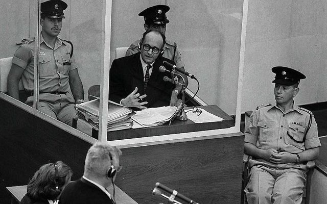 Le criminel de guerre nazi Adolph Eichmann se trouve dans une cabine de verre protectrice entouré par la police israélienne lors de son procès le 22 juin 1961 à Jérusalem. (Photo par GPO)