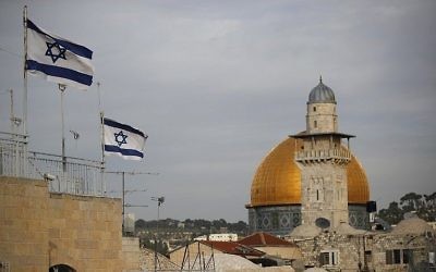 Les drapeaux israéliens flottent au vent alors que le Dôme du Rocher est vu en arrière-plan, dans la Vieille Ville de Jérusalem, le 5 décembre 2017. (Crédit : AFP / Thomas Coex)
