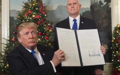 Le président américain Donald Trump tient un mémorandum signé après avoir prononcé son discours concernant Jérusalem depuis la Maison-Blanche, à Washington, le 6 décembre 2017, sous le regard du vice-président américain Mike Pence (Crédit : Saul Loeb / AFP)