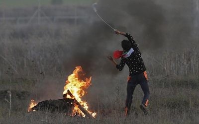 Un émeutier palestinien lance une pierre sur les soldats israéliens pendant des affrontements près de la frontière entre l'Etat juif et Gaza, suite à a reconnaissance par Trump de Jérusalem comme capitale israélienne, le 9 décembre 2017(Crédit : AFP/Mahmud Hams) Un émeutier palestinien lance une pierre sur les soldats israéliens pendant des affrontements près de la frontière entre l'Etat juif et Gaza, suite à a reconnaissance par Trump de Jérusalem comme capitale israélienne, le 9 décembre 2017(Crédit : AFP/Mahmud Hams)