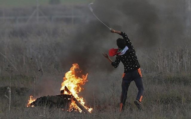 Un émeutier palestinien lance une pierre sur les soldats israéliens pendant des affrontements près de la frontière entre l'Etat juif et Gaza, suite à a reconnaissance par Trump de Jérusalem comme capitale israélienne, le 9 décembre 2017(Crédit : AFP/Mahmud Hams) Un émeutier palestinien lance une pierre sur les soldats israéliens pendant des affrontements près de la frontière entre l'Etat juif et Gaza, suite à a reconnaissance par Trump de Jérusalem comme capitale israélienne, le 9 décembre 2017(Crédit : AFP/Mahmud Hams)