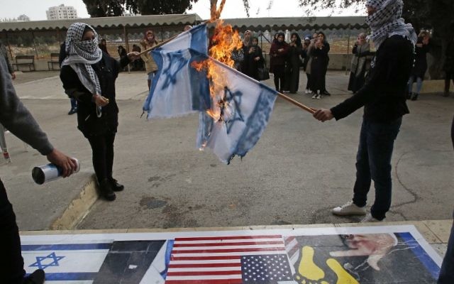 Des Palestiniens brûlent des drapeaux israéliens lors d'une manifestation à l'Université ouverte d’Al-Quds dans le village de Dura, à la périphérie de la ville de Hébron le 13 décembre 2017, alors que les protestations se poursuivent dans la région suite à la reconnaissance de Jérusalem comme capitale d’Israël par Donald Trump (PHOTO AFP / HAZEM BADER)