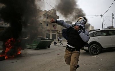 Des manifestants palestiniens affrontent les forces de l'ordre israéliennes près du checkpoint de Qalandiya, en Cisjordanie, le 20 décembre 2017, après la reconnaissance de Jérusalem comme capitale d'Israël par Donald Trump. (Crédit : AFP / ABBAS MOMANI)