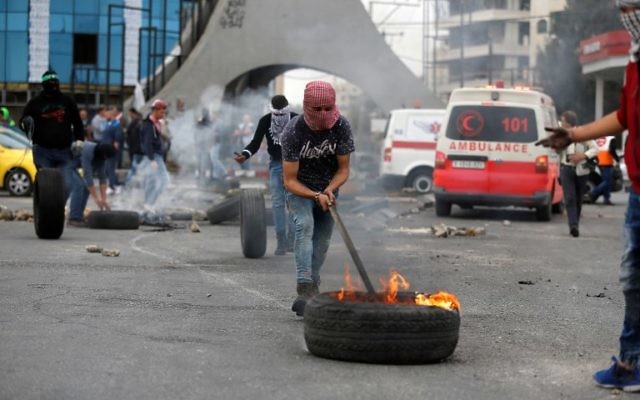 Des manifestants palestiniens brûlent des pneus durant une manifestation au nord de Ramallah, le 22 décembre 2017. (Crédit : AFP/Abbas MOMANI) Des manifestants palestiniens brûlent des pneus durant une manifestation au nord de Ramallah, le 22 décembre 2017. (Crédit : AFP/Abbas MOMANI)