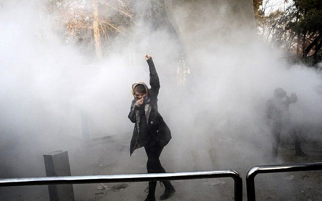 Une Iranienne lève le poing dans la fumée des gaz lacrymogènes à l'université de Téhéran durant une manifestation contre les problèmes économiques dans la capitale iranienne, le 30 décembre 2017 (Crédit : AFP PHOTO / STR)