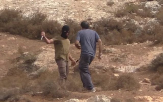 Un extrémiste de droite masqué attaque Arik Ascherman, chef de l'ONG Rabbis for Human Rights. (Crédit : capture d'écran Youtube)