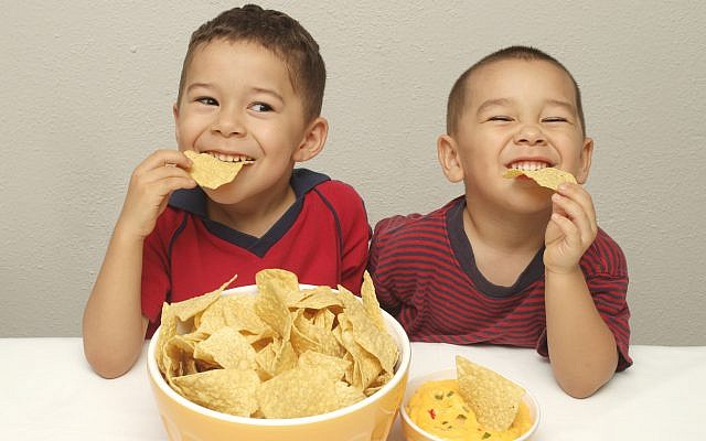 Illustration : deux enfants espagnols mangent des chips. (Crédit : (Hugh Stonelan via Stock/Getty Images)