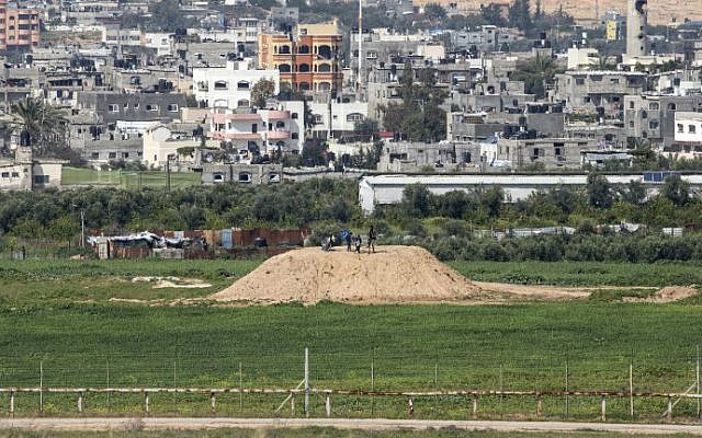Une photo prise depuis le côté israélien de la frontière avec Gaza montre un Palestinien et des enfants au sommet d'un avant-poste du Hamas le long de la frontière, le 25 février 2016 (Jack Guez / AFP) Une photo prise depuis le côté israélien de la frontière avec Gaza montre un Palestinien et des enfants au sommet d'un avant-poste du Hamas le long de la frontière, le 25 février 2016 (Jack Guez / AFP)