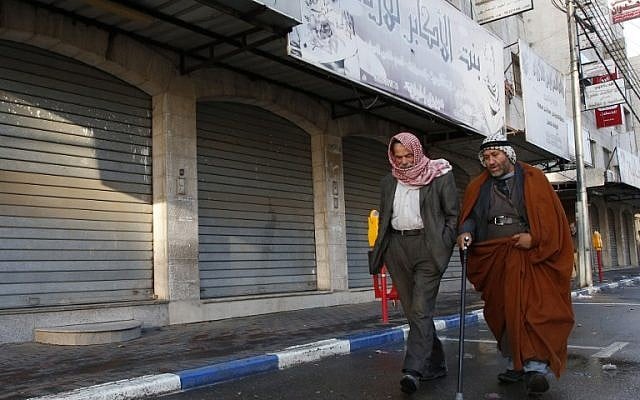 Illustration : Des Palestiniens marchent devant les magasins fermés dans la ville de Hébron en Cisjordanie, après un appel à la grève générale pour protester contre la décision prise par le président américain Donald Trump de reconnaître Jérusalem en tant que capitale d'Israël, le 7 décembre 2017 (Crédit : (HAZEM BADER/AFP) Illustration : Des Palestiniens marchent devant les magasins fermés dans la ville de Hébron en Cisjordanie, après un appel à la grève générale pour protester contre la décision prise par le président américain Donald Trump de reconnaître Jérusalem en tant que capitale d'Israël, le 7 décembre 2017 (Crédit : (HAZEM BADER/AFP)
