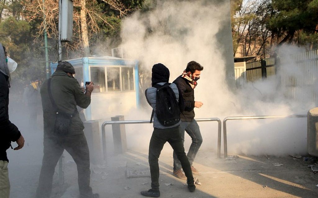 Des étudiants fuient les tirs de gaz lacrymogènes devant l'université de Téhéran durant une manifestation contre les problèmes économiques dans la capitale iranienne, le 30 décembre 2017. Les étudiants ont manifesté pour un troisième jour en raison des problèmes de l'économie iranienne, comme l'ont montré des vidéos sur les réseaux sociaux. Mais leur nombre a été surpassé par les contre-manifestants (Crédit :  AFP / STR)