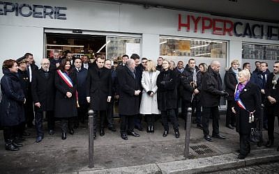 La maire de Paris Anne Hidalgo (4ème g), le président français Emmanuel Macron (5ème g), le ministre français de l'Intérieur Gérard Collomb (6ème), le porte-parole du gouvernement français Benjamin Griveaux (C), la femme du président Brigitte Macron (6ème) rendent hommage lors d'une cérémonie commémorative devant le supermarché Hyper Casher aux victimes du magasin casher qui ont été tuées il y a trois ans par un terroriste islamiste à Paris, le 7 janvier 2018. (Crédit : AFP / POOL / CHRISTIAN HARTMANN)