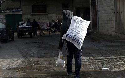 Un jeune Palestinien transporte un colis alimentaire de l'UNRWA à Gaza City, le 15 janvier 2018. (Crédit : MOHAMMED ABED / AFP)