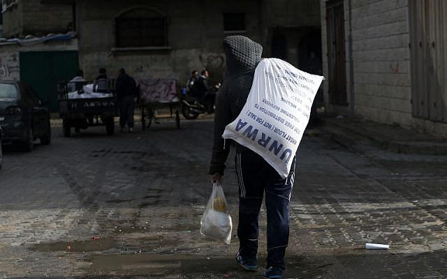 Un jeune Palestinien transporte un colis alimentaire de l'UNRWA à Gaza City, le 15 janvier 2018. (Crédit : MOHAMMED ABED / AFP)