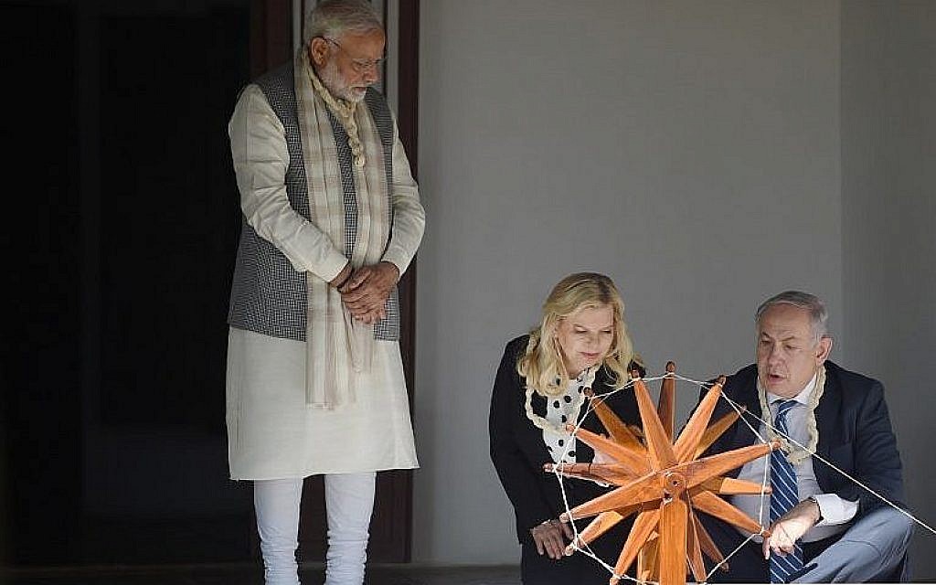 Le Premier ministre Benjamin Netanyahu, à droite, utilise un rouet alors que son épouse  Sara Netanyahu et le Premier ministre indien  Narendra Modi l'observent durant une visite à Gandhi Ashram à Ahmedabad on le 17 janvier 2018 (Crédit :  AFP/SAM PANTHAKY)