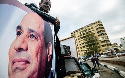 Un sympathisant du président égyptien Abdel Fattah el-Sissi se tient à l'arrière d'une camionnette arborant son portrait et ses haut-parleurs, sur la place Tahrir de la capitale, le 25 janvier 2018, alors que le pays marque le septième anniversaire du soulèvement de 2011 qui a mis fin au règne de 30 ans de l'ancien président Hosni Mubarak. (Crédit : AFP / MOHAMED EL-SHAHED)
