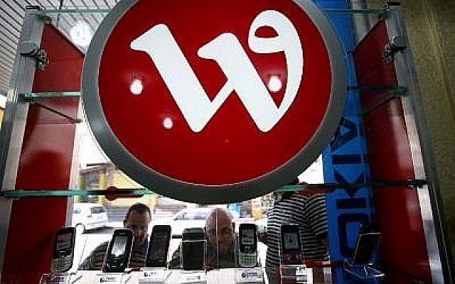 Des Palestiniens regardent des téléphones portables disposés sous le logo de la compagnie de téléphone palestinienne Wataniya, dans un magasin de Jénine, en Cisjordanie, le 14 octobre 2009 (Crédit : AFP / Saif Dahlah)