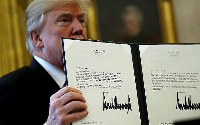 Le président américain Donald Trump brandit une copie de la législation avant de promulguer le projet de loi sur la réforme fiscale depuis le bureau ovale, le 22 décembre 2017 à Washington (Chip Somodevilla / Getty Images / AFP)
