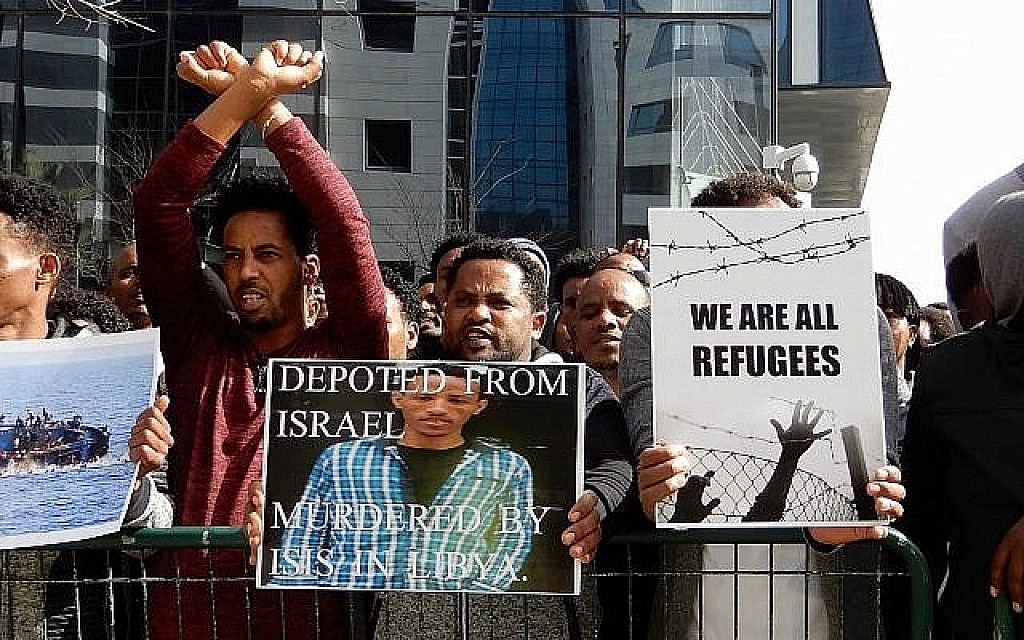 Les amis de Tesfe Kidane (aucun lien avec Helen Kidane), un demandeur d'asile érythréen déporté au Rwanda il y a deux ans, brandissent sa photo lors d'une manifestation devant l'ambassade rwandaise à Herzliya le 22 janvier 2018. Kidane a été assassiné en Libye en essayant de fuir vers l'Europe. (Melanie Lidman / Times of Israël)