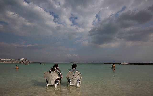 Des gens assis près de l'eau sur la plage de Hamei Zohar sur les rives de la mer Morte, le 10 novembre 2015 (Nati Shohat / Flash90)