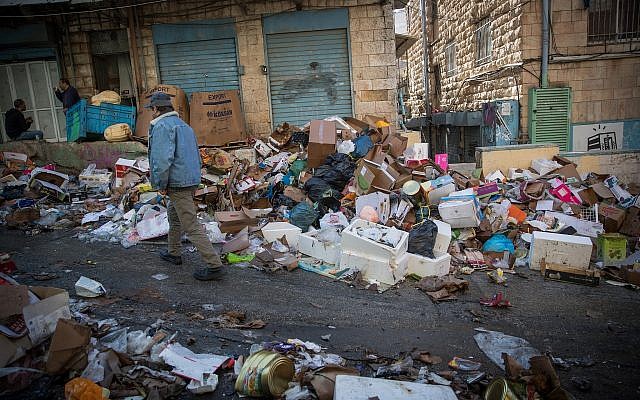 Les clients passent devant des piles d'ordures laissées par des ouvriers de la ville en grève, au Marché Mahane Yehuda de Jérusalem, le 7 janvier 2018. (Yonatan Sindel / Flash90) Les clients passent devant des piles d'ordures laissées par des ouvriers de la ville en grève, au Marché Mahane Yehuda de Jérusalem, le 7 janvier 2018. (Yonatan Sindel / Flash90)
