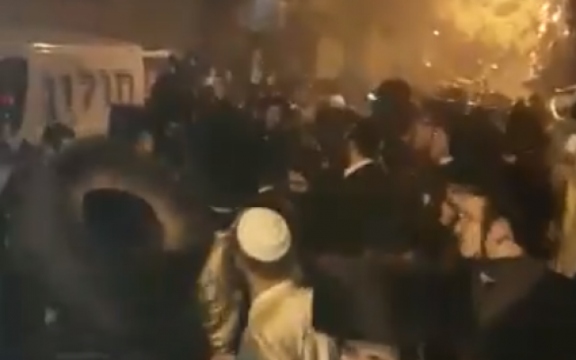 Des centaines de manifestants ultra-orthodoxes s'opposent à la police en tentant de bloquer un véhicule transportant un cadavre à une possible autopsie aux premières heures de la journée, le 21 janvier 2018 (Capture d'écran/Twitter)