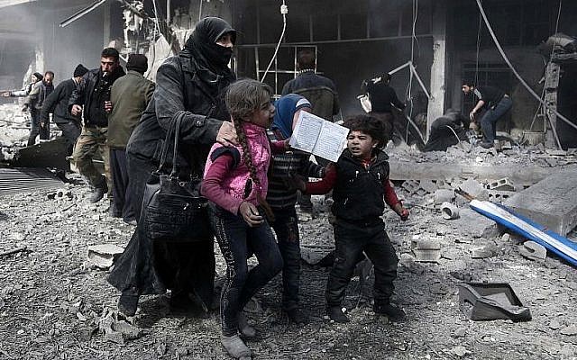 Une femme syrienne et des enfants courent pour trouver un abri   après un bombardement gouvernemental dans la ville d' Hammuriyeh, détenue par les rebelles,  à la Ghouta orientale, détenue par les rebelles, aux abords de Damas, le 19 février 2018 (Crédit :  AFP PHOTO /Abdulmonan Eassa)