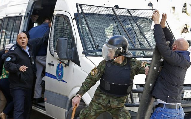 La police palestinienne empêche des manifestants d'approcher un véhicule transportant des membres du conseil municipal de New York et des groupes de la société civile alors qu'ils quittent un immeuble après avoir visité une ONG dans la ville de Ramallah, en Cisjordanie, le 22 février 2018 (Crédit : Abbas Momani/AFP)