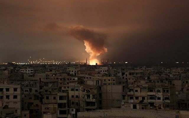 De la fumée s'élève suite à une frappe aérienne du régime sur la région assiégée de la Ghouta orientale aux abords de la capitale de Damas, dans la nuit du 23 février 2018 (Crédit : AFP/ Ammar SULEIMAN) De la fumée s'élève suite à une frappe aérienne du régime sur la région assiégée de la Ghouta orientale aux abords de la capitale de Damas, dans la nuit du 23 février 2018 (Crédit : AFP/ Ammar SULEIMAN)