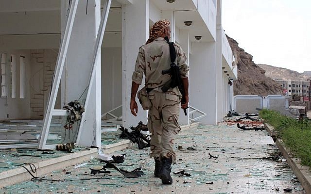 Un combattant du conseil de transition du sud séparatiste marche sur le site de deux attentats-suicides à la voiture piégée qui ont ciblé le siège d'une unité terroriste le jour précédent, dans le port d'Aden, dans le sud du Yémen, le 25 février 2018 (Crédit : AFP PHOTO / SALEH AL-OBEIDI)