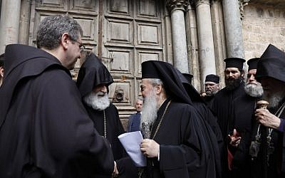 Le patriarche grec-orthodoxe de Jérusalem Théophile III lit un communiqué à la presse aux côtés du gardien de la terre sainte, le frère Francesco Patton et de l'évêque arménien Siwan,à gauche, devant les portes closes de l'église du saint-sépulcre, dans la Vieille Ville de Jérusalem, le 25 février 2018 (Crédit : AFP/ GALI TIBBON)