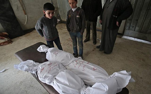 Des enfants devant des cadavres emballés, après des frappes du régime dans la Ghouta orientale, en périphérie de Damas, le 5 février 2018. (Crédit : AFP / ABDULMONAM EASSA) Des enfants devant des cadavres emballés, après des frappes du régime dans la Ghouta orientale, en périphérie de Damas, le 5 février 2018. (Crédit : AFP / ABDULMONAM EASSA)