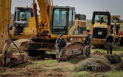 Des agents de la police des frontières surveillent près des tracteurs pendant les préparatifs pour l'évacuation et la démolition de l'avant-poste illégal de Netiv Haavot le 7 février 2018. (Gershon Elinson/Flash90)