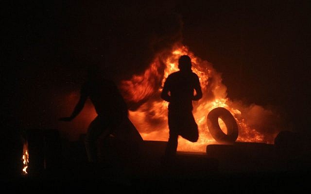 Des Palestiniens brûlent des pneus lors d'affrontements avec la police des frontières israélienne au poste de contrôle de Qalandiya, entre Jérusalem et Ramallah, le 24 juillet 2014, à la suite d'une marche massive de 10 000 manifestants palestiniens contre l'offensive militaire israélienne dans la bande de Gaza. (Photo : Issam Rimawi/FLASH90) Des Palestiniens brûlent des pneus lors d'affrontements avec la police des frontières israélienne au poste de contrôle de Qalandiya, entre Jérusalem et Ramallah, le 24 juillet 2014, à la suite d'une marche massive de 10 000 manifestants palestiniens contre l'offensive militaire israélienne dans la bande de Gaza. (Photo : Issam Rimawi/FLASH90)