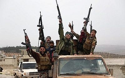 Des rebelles syriens soutenus par la Turquie font signe en descendant une route dans la région de Hallubi, au nord d'Afrin, le 8 mars 2018. (AFP PHOTO / Nazeer al-Khatib)