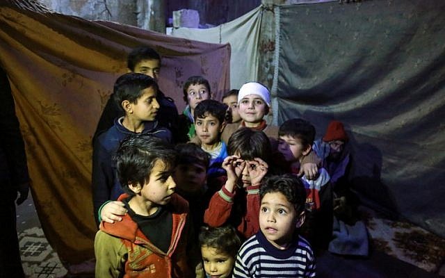 Les enfants syriens posent pour une photo dans un abri antiaérien artisanal dans la ville de Douma, détenue par les rebelles, dans la Ghouta orientale, située dans les faubourgs de  Damas, le 8 mars 2018 (Crédit : AFP PHOTO / HAMZA AL-AJWEH