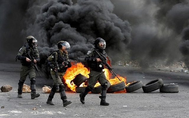 Les gardes-frontières israéliens dans une rue durant des affrontements avec des manifestants palestiniens protestant contre le transfert de l'ambassade américaine à Jérusalem, dans la ville de Ramallah, en Cisjordanie, le 9 mars 2018 (Crédit : / AFP PHOTO / ABBAS MOMANI) Les gardes-frontières israéliens dans une rue durant des affrontements avec des manifestants palestiniens protestant contre le transfert de l'ambassade américaine à Jérusalem, dans la ville de Ramallah, en Cisjordanie, le 9 mars 2018 (Crédit : / AFP PHOTO / ABBAS MOMANI)