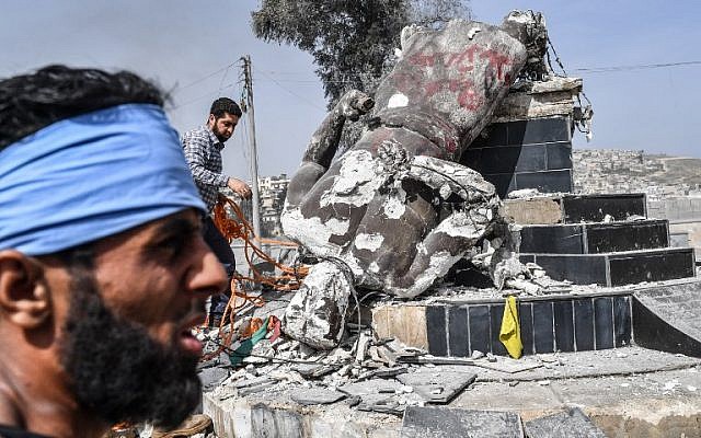 Des rebelles syriens soutenus par les Turcs retirent une corde de la statue de "Kawa", le forgeron qui était une figure centrale dans une légende kurde sur la célébration du nouvel an de Norouz, après l'avoir détruite dans la ville d'Afrin dans le nord de la Syrie le 18 mars 2018. (AFP PHOTO / BULENT KILIC)