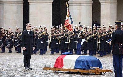Le président français Emmanuel Macron (à gauche) se tient près du cercueil du lieutenant-colonel Arnaud Beltrame, après lui avoir décerné à titre posthume la médaille de commandant de l'Ordre de la Légion d'honneur lors d'une cérémonie nationale le 28 mars 2018 à l'Hôtel des Invalides à Paris. (Ludovic MARIN / POOL / AFP)