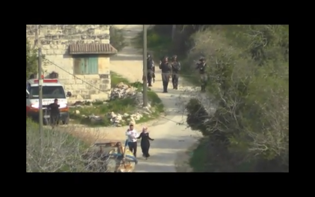 Des soldats israéliens jettent une grenade incapacitante en direction d'un couple palestinien portant un bébé (Capture d'écran : Yesh Din) Des soldats israéliens jettent une grenade incapacitante en direction d'un couple palestinien portant un bébé (Capture d'écran : Yesh Din)