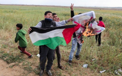 Des enfants de la bande de Gaza agitent un drapeau palestinien et brûle un drapeau à l'effigie de Donald Trump, le 30 mars 2018 (Crédit : Said Khatib/AFP)