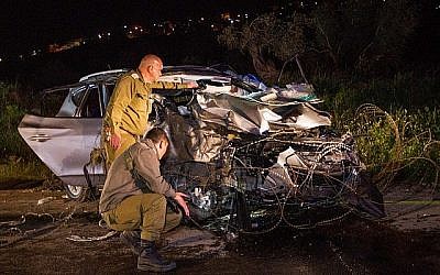 Des soldats israéliens inspectent une voiture sur les lieux où deux soldats israéliens ont été tués et deux autres blessés lors d'un attentat terroriste  à la voiture-bélier près de Mevo Dotan, en Cisjordanie, le 16 mars 2018. (Meir Vaknin/Flash90)