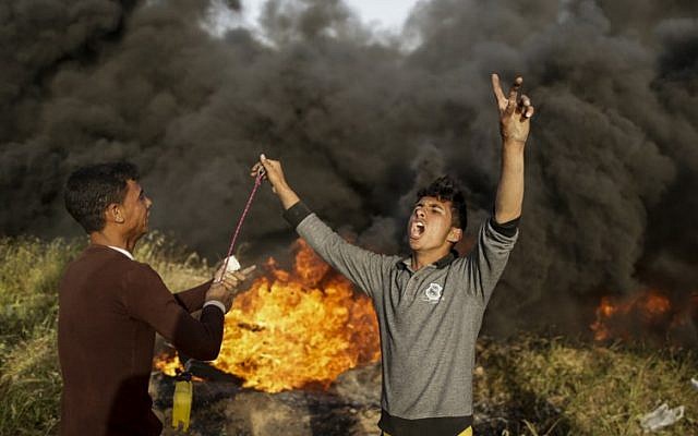 Des manifestants palestiniens scandent des slogans durant des affrontements avec les forces israéliennes suite à un rassemblement à la frontière entre Israël et Gaza, à l'est de Gaza City, le 4 avril 2018 (Crédit : AFP PHOTO / MAHMUD HAMS) Des manifestants palestiniens scandent des slogans durant des affrontements avec les forces israéliennes suite à un rassemblement à la frontière entre Israël et Gaza, à l'est de Gaza City, le 4 avril 2018 (Crédit : AFP PHOTO / MAHMUD HAMS)