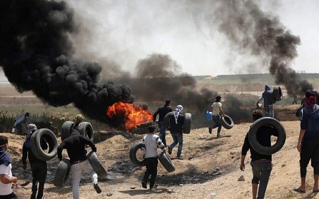 Des hommes palestiniens collectent des pneus et les brûlent pour se protéger des tirs de soldats israéliens à la frontière entre Israël et Gaza lors d'une manifestation à l'est de la ville de Gaza, le 6 avril 2018 (Crédit : AFP PHOTO / MAHMUD HAMS) Des hommes palestiniens collectent des pneus et les brûlent pour se protéger des tirs de soldats israéliens à la frontière entre Israël et Gaza lors d'une manifestation à l'est de la ville de Gaza, le 6 avril 2018 (Crédit : AFP PHOTO / MAHMUD HAMS)